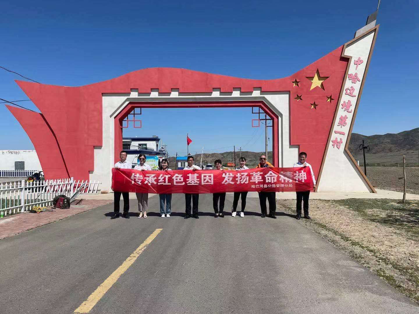 哈巴河公路管理分局党员干部代表在萨尔乌楞村红色拱门处合影 图：海尼·吾木尔扎克.jpg