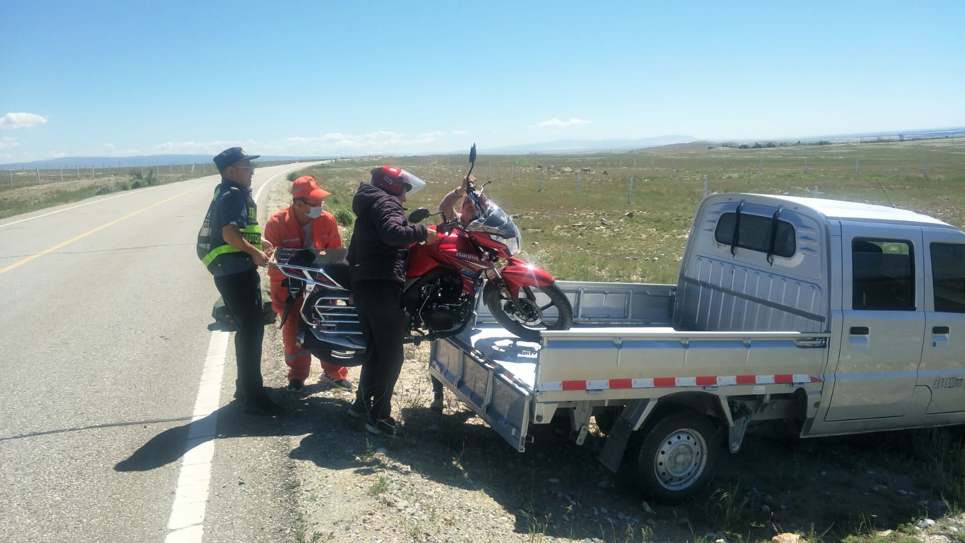 哈巴河公路管理分局与阿勒泰执法支队哈巴河执法大队职工协助牧民将摩托车抬上车斗 图：王文龙.jpg