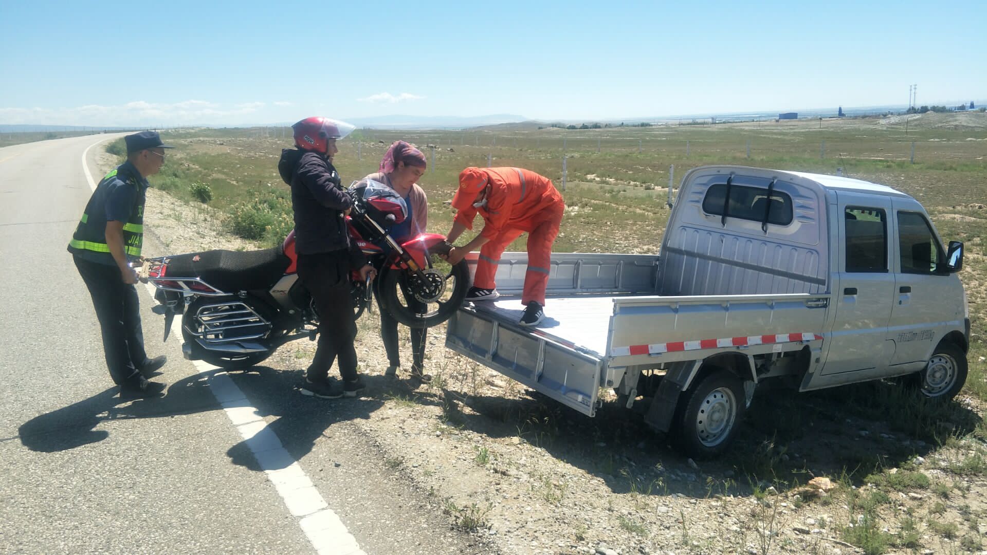 哈巴河公路管理分局闫金辉与阿勒泰执法支队哈巴河执法大队孙先超帮助牧民将摩托车抬上车斗 图：王文龙.jpg